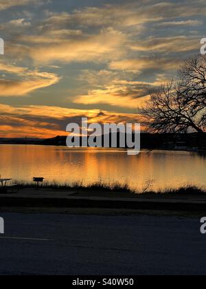 Coucher de soleil sur le lac Inks. Situé dans le parc national d'Inks Lake, Texas. Célébration de 100 ans dans les parcs nationaux du Texas. La belle réflexion des rayons du soleil comme son reflet des rayons d'or de l'eau. Banque D'Images