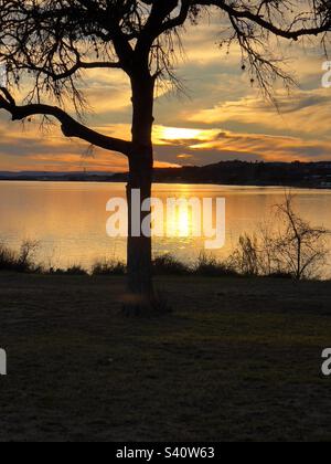 Coucher de soleil sur le lac Inks. Situé dans le parc national d'Inks Lake, Texas. Célébration de 100 ans dans les parcs nationaux du Texas. La belle réflexion du soleil comme ses rayons dorés se reflètent au large du lac. Banque D'Images