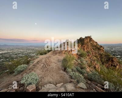 Vue sur l'arrière du chameau depuis l'héliport de secours, le sentier de la Jolla, la montagne de Camelback, la lune au-dessus des banlieues dans le ciel est rose et pourpre en fondu au coucher du soleil, Scottsdale, Phoenix Arizona, l'espace de copie Banque D'Images