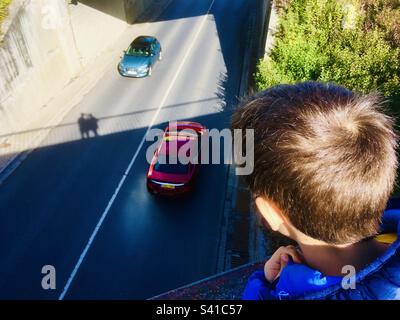 Enfant qui regarde depuis le pont vers les voitures Banque D'Images