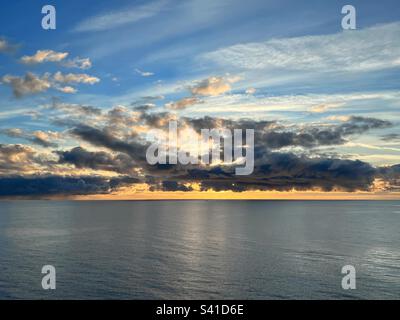 Horizon paisible au-dessus de la mer Baltique avec lumière du soleil au lever du soleil derrière les nuages sombres Banque D'Images