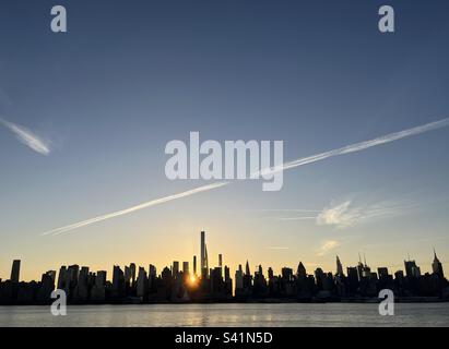 Lever de soleil derrière les gratte-ciel de New York tout en traversant l'Hudson Banque D'Images