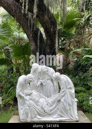 Un arbre tours plus de 14th station, stations de la croix, Jésus est posé dans le tombeau, blanc presque grandeur nature statues, contrastant avec le jardin verdant de la végétation d'Eden Banque D'Images