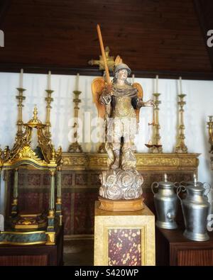 L'Archange St Michael, entouré d'objets historiques de l'église tels que des cruches à laver les pieds vues dans la chapelle du 17th siècle à Faro Sé au Portugal Banque D'Images