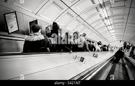 Les personnes qui descendent l'escalier roulant dans une station de métro de Londres au Royaume-Uni Banque D'Images