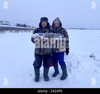 Yakuts Asiatiques pêcheurs couple mudchina et une femme garder un gros poisson en hiver sur la glace et la neige à Yakutia. Banque D'Images