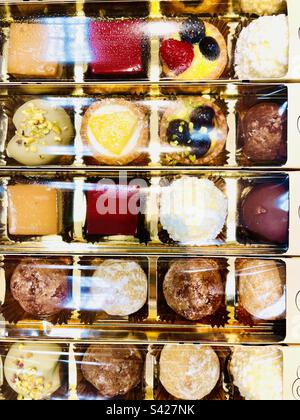 Différents types de petits gâteaux de pâtisserie enveloppés dans une boîte en plastique doré Banque D'Images
