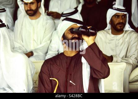 Sheikh Mohammed bin Rashid Al Maktoum leade de Dubaï, regardant à travers ses jumelles pendant le derby de chameau. Banque D'Images