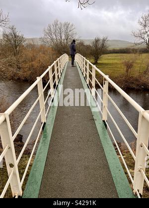 Homme debout sur une passerelle au-dessus de la rivière Ure à Wensleydale Banque D'Images