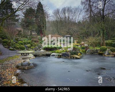 Jardin japonais avec lanternes en pierre et étang gelé à Würzburg, Allemagne. Banque D'Images