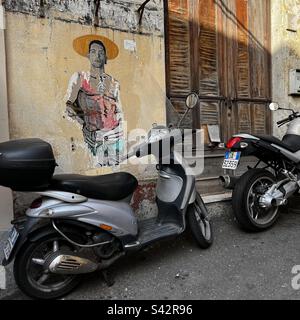 Scooters garés en face de l'art de la rue et des volets en bois à Taormina, Sicile Banque D'Images