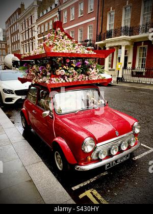 Mini rouge vintage avec fleurs sur le toit à Mayfair, Londres Banque D'Images