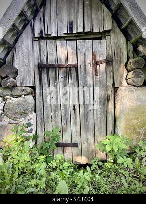 Porte en bois de la cave construite en pierres dans la campagne de Lettonie. Banque D'Images