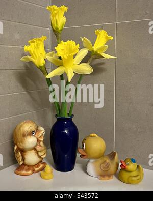 Salle de bains encore vie. Jonquilles en vase bleu et canards en caoutchouc jaune Banque D'Images