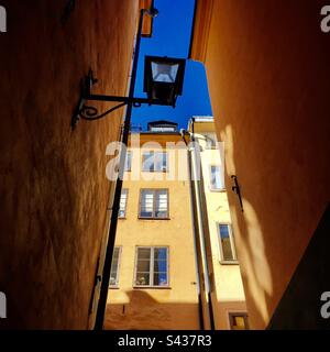 Les magnifiques extérieurs peints orange et jaune ombrageux des bâtiments traditionnels sur les rues étroites de la vieille ville de Stockholm Gamla Stan en Suède Banque D'Images