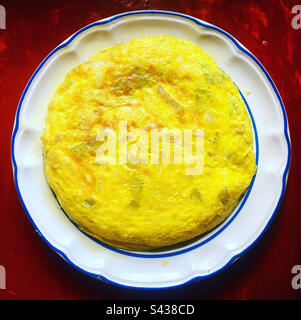 Une tortilla espagnole avec des œufs, des pommes de terre et des oignons dans une assiette sur une table rouge au Mexique Banque D'Images