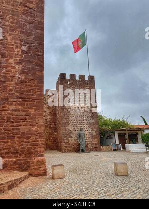 Statue du roi Dom Sancho I en face de la tour du château de Silves avec drapeau portugais en Algarve. Banque D'Images