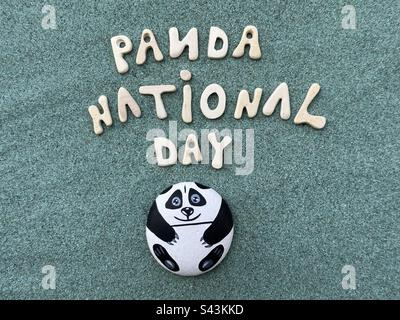 La Journée nationale de Panda a été célébrée avec du panda peint à la main sur une pierre, des lettres en bois faites à la main sur du sable vert Banque D'Images