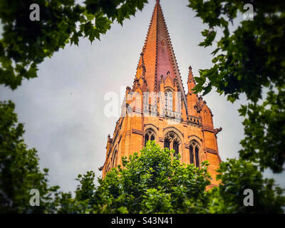 Spire of St.Paul's Cathedral à Melbourne, Victoria, Australie, entouré de feuilles d'arbres vertes. Style de transition néo-gothique. Banque D'Images