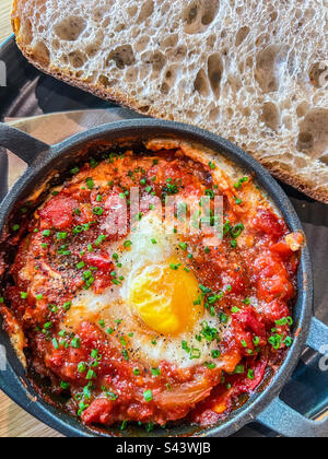 Shakshuka aux œufs cuits avec pain au levain servi dans une poêle à repasser Banque D'Images