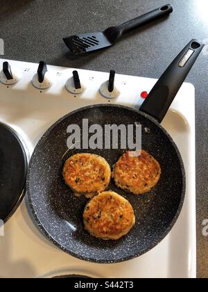 Galettes de saumon et de poisson dans une poêle Banque D'Images