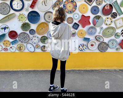 Adolescent touriste regardant les assiettes accrochées à l'extérieur d'une boutique de poterie dans l'Algarve Banque D'Images