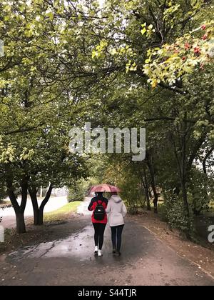 Deux personnes sous un parapluie dans le parc de la ville Banque D'Images