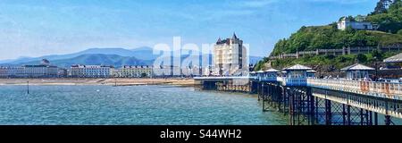 Vue panoramique depuis la jetée de Llandudno, dans le nord du pays de Galles, en direction du Grand Hotel, de la Promenade et des montagnes de Snowdonia en arrière-plan Banque D'Images