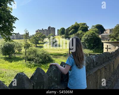 Fille de 8 ans qui regarde par-dessus le pont vers le château d'Alnwick, dans le Northumberland, Royaume-Uni Banque D'Images