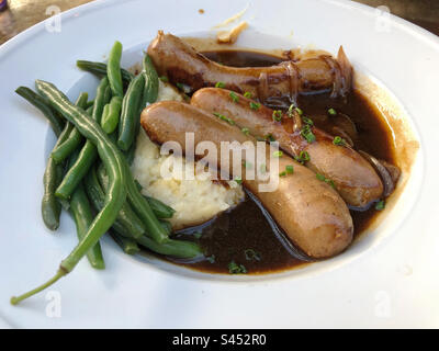 Les bangers britanniques et le repas de purée avec des haricots verts. Banque D'Images