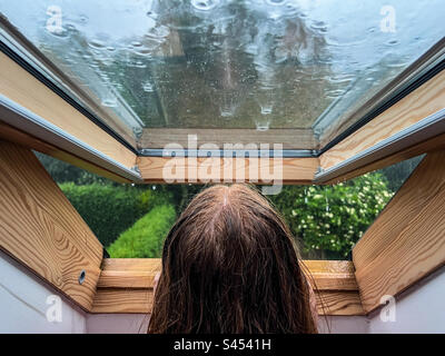 Adolescent regardant par la fenêtre pendant l'orage et la pluie Banque D'Images