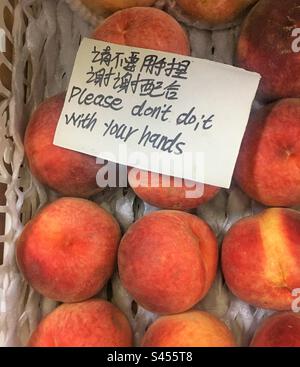 Une note dans une boîte avec des pêches. Drôle de signe anglais mal traduit du chinois. Banque D'Images