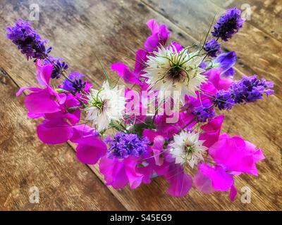 Petit bouquet de pois sucrés roses, lavande violette et amour blanc dans une brume fleurs dans un vase sur une table en bois, par le haut Banque D'Images