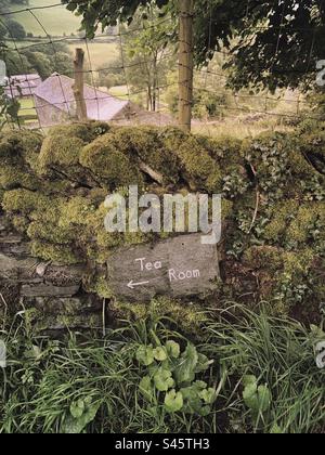 Un panneau de direction de salon de thé écrit sur une ardoise sur un mur de pierre sèche couvert de mousse typique dans le Lake District anglais, Royaume-Uni - salon de thé de campagne britannique Banque D'Images