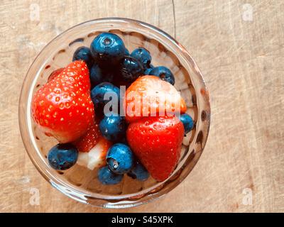Gros plan de bleuets et de fraises d'été frais colorés dans un petit bol en verre. Banque D'Images