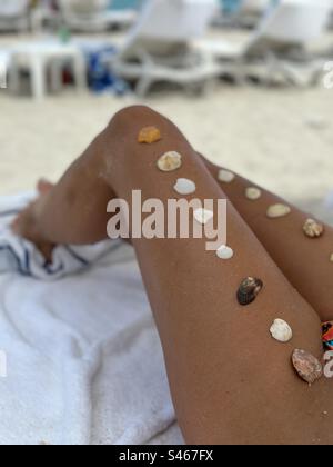 Bronzer les jambes des femmes avec coquillages alignés sur les jambes Banque D'Images