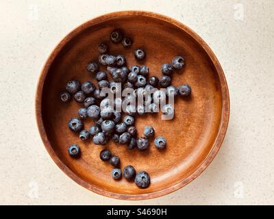 Plusieurs myrtilles, un motif de dispersion, dans un bol circulaire en bois. Frais, coloré, juteux, sucré, nutritif, fruits d'été. Banque D'Images
