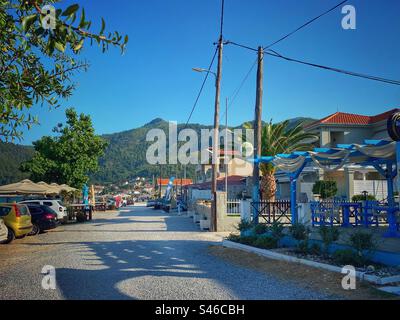 Vue sur la rue avec colline verte en arrière-plan dans la station balnéaire de Skala Potamias sur l'île de Thassos, Grèce. Banque D'Images