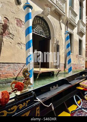 Poteaux d'amarrage rayés bleu et blanc vues de la gondole noire ornée sur le canal Rio del Pestrin, Venise Banque D'Images