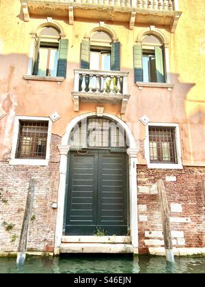 Maison de canal avec des teintes roses et jaunes sur pierre avec des briques rouges et un accent de porte verte sur Rio di San Felipe, quartier Cannaregio, Venise Banque D'Images