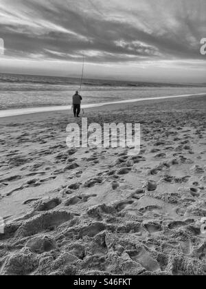 Pêcheur à la plage de Lagoa de Albufeira dans le comté de Setubal (région de Sesimbra, sud du Portugal). Image monochromatique au coucher du soleil. Banque D'Images