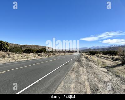 Vue depuis le bord de la route, à côté d'un tronçon plat d'autoroute à travers le désert dans le sud de la Californie Banque D'Images