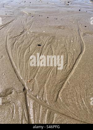 Lignes ondulées dans le sable sur la plage créées par l'eau qui coule Banque D'Images