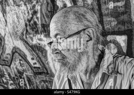 Portrait monochrome de l'homme âgé contre le mur de graffiti Banque D'Images