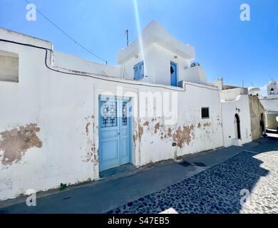 Bâtiment blanchi à la chaux avec portes et volets bleus dans le village traditionnel de Megalochori sur l'île de Santorin. Banque D'Images