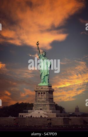 La Statue de la liberté avec un ciel de coucher de soleil dramatique Banque D'Images