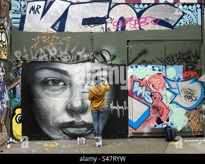 Un artiste graffiti peint une œuvre sur le Southbank à Londres, en Angleterre. Banque D'Images