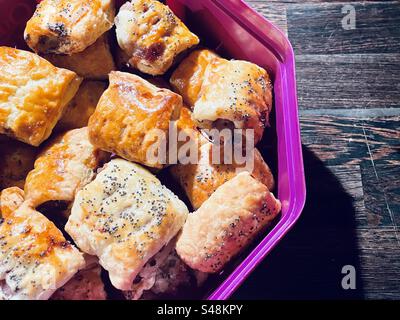 Petits pains de saucisse fraîchement préparés dans une baignoire Quality Street vide. Banque D'Images