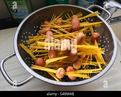 Plan rapproché d'une passoire avec mini hot-dogs et pâtes spaghetti Banque D'Images