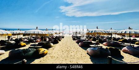 Vue panoramique du bar de plage à Seminyak Bali prêt pour les boissons au coucher du soleil avec parasols et poufs Banque D'Images